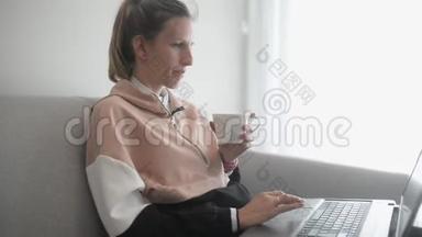 年轻<strong>女子坐在沙发上</strong>用电脑工作